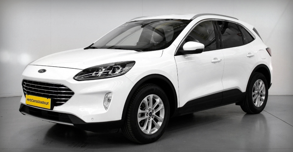 ford kuga branco com vidros traseiros escurecidos e por trás um painel branco com o logotipo da Hertz Carros Usados